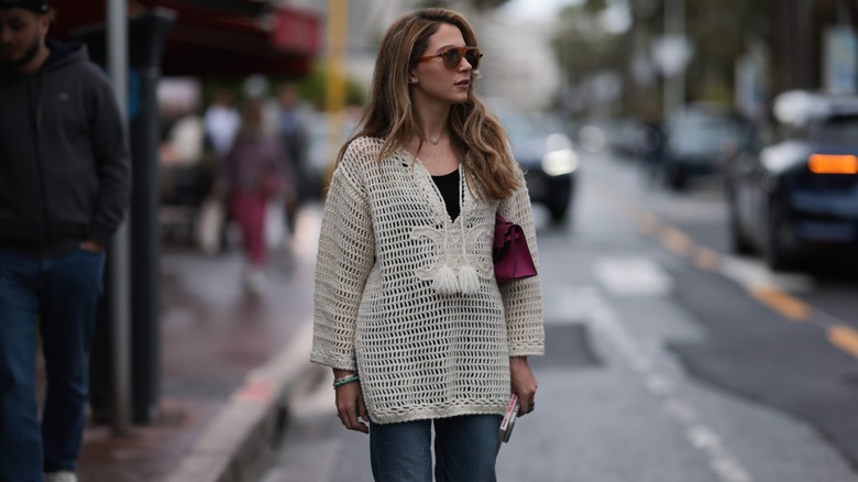 Woman wearing open-knit sweater, jeans