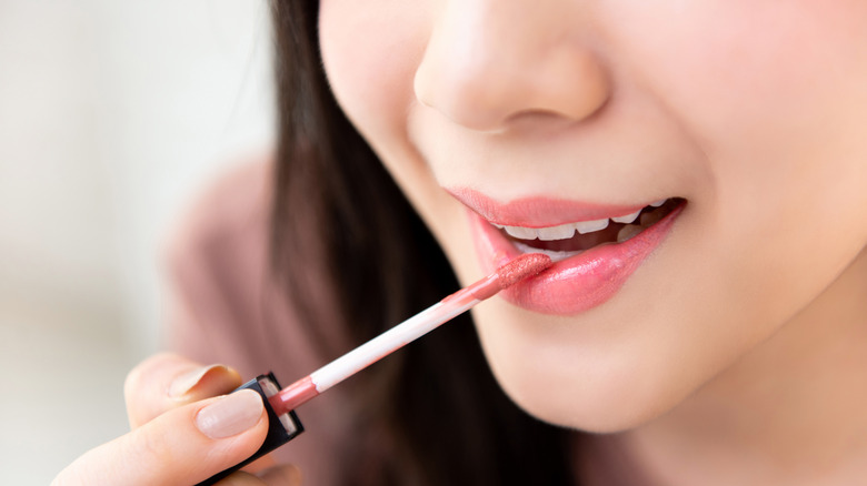 Close up of model applying lipgloss