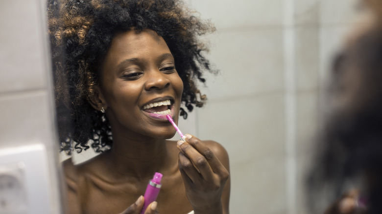 A woman applying lip gloss