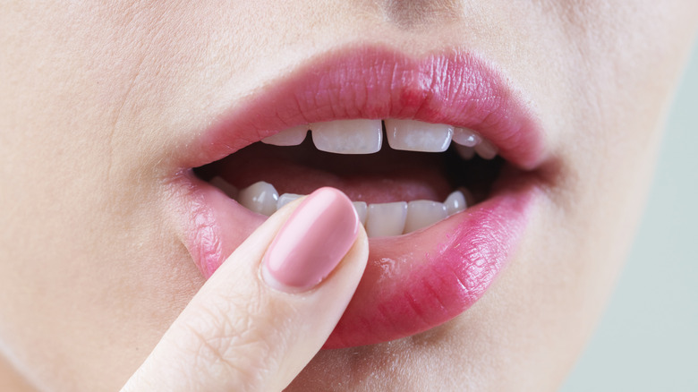 Female finger touching lips, wearing lipstick