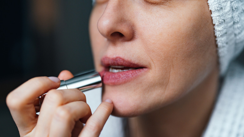 Woman applying lipstick from a silver tube