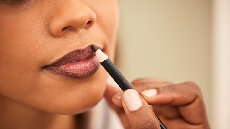 Woman applying dark lipliner to her lips