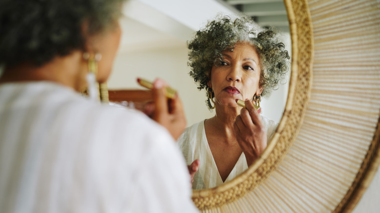 Woman looking in the mirror with red lipstick