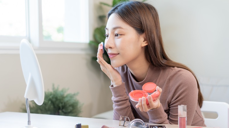 woman applying cream blush