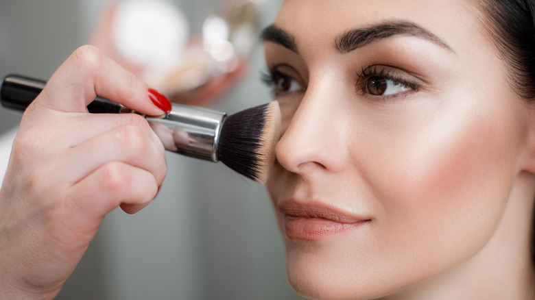 Makeup artist applying highlight to woman