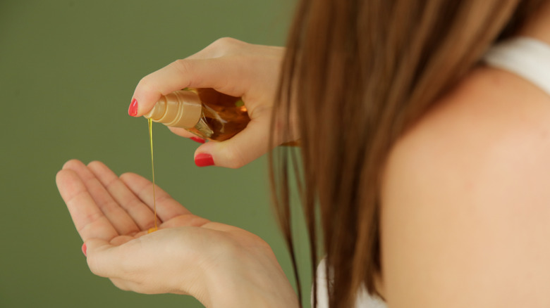 Woman putting oil on hair 