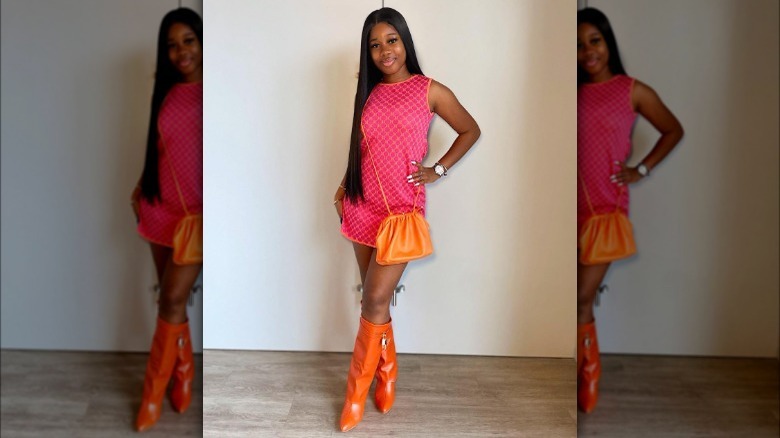 Model wearing orange fold-over boots and fuchsia dress