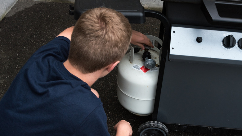 man checking propane tank on grill