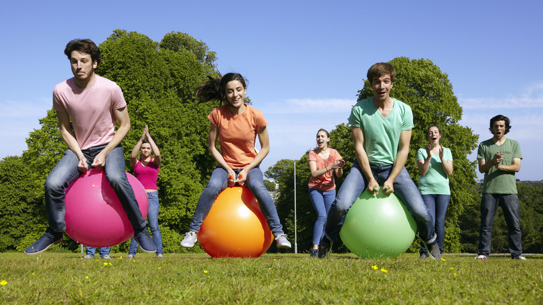 people bouncing on balls outside