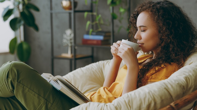 woman holding coffee reading book