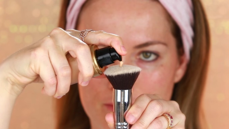 Woman applies foundation to brush