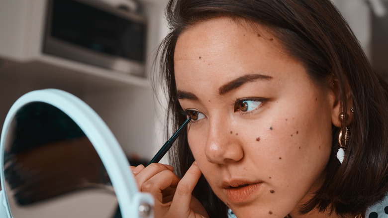 A woman applying eyeliner
