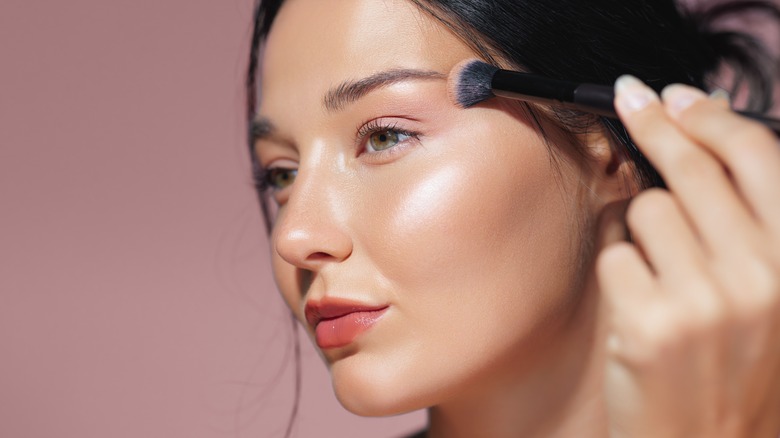 Woman applying shimmer to her face