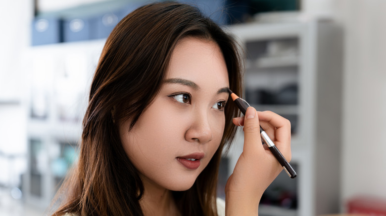 Woman drawing her eyebrows