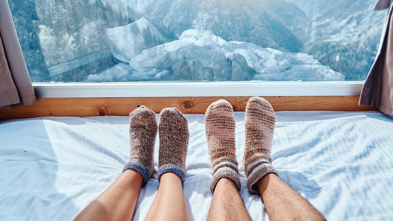 two feet wearing socks in a bed overlooking snow-capped mountains