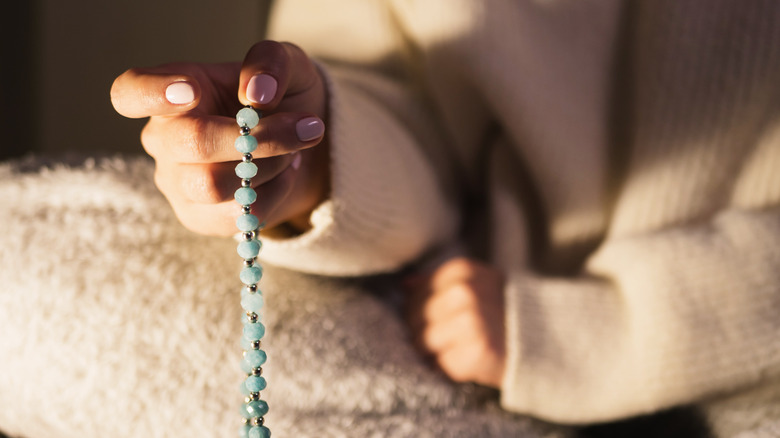 Person holding mala beads in hand