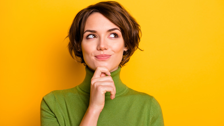 woman smiling and thinking with yellow orange backdrop