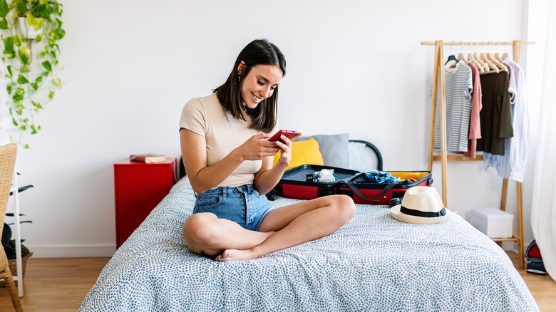 texting woman with suitcase