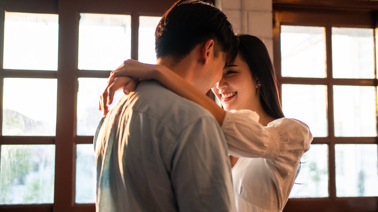 Couple kisses in front of window