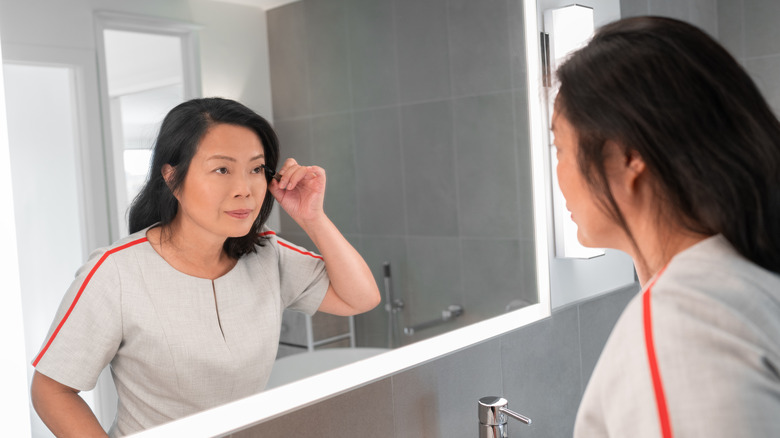 Woman looking in the mirror applying mascara