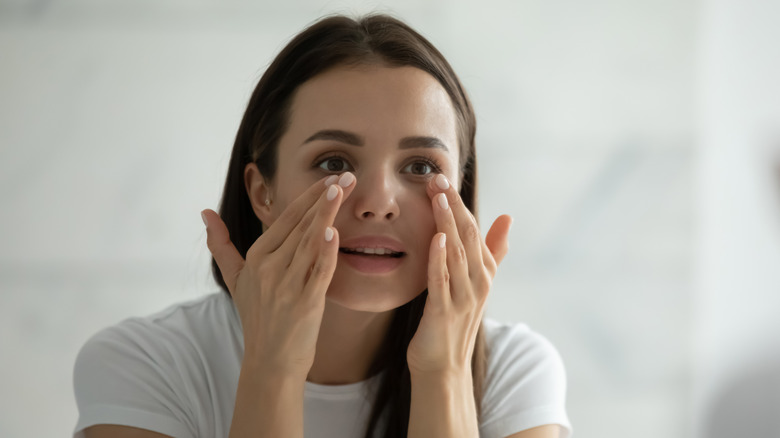 Woman applying cream under eyes