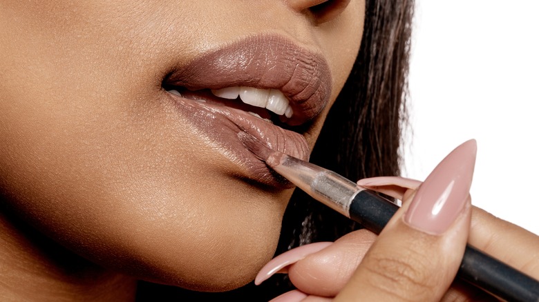 woman applying lipstick with a brush