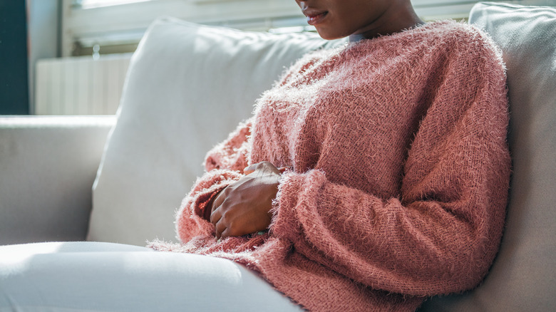 Woman holds tummy in pain