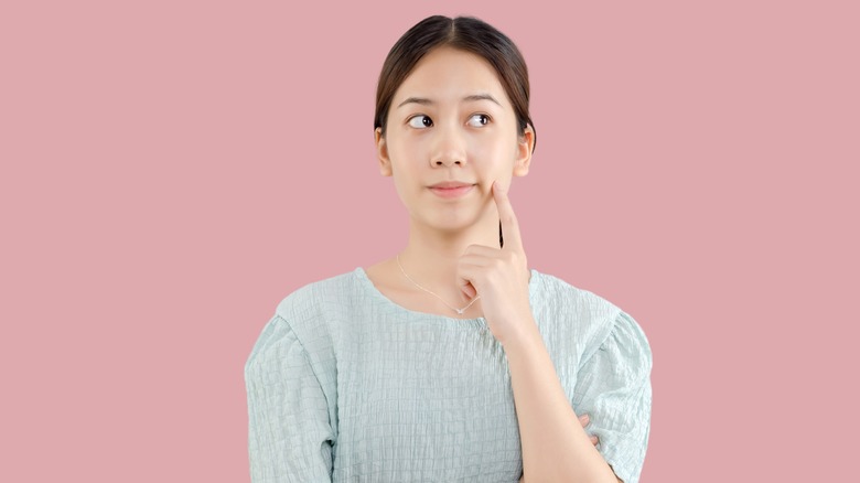 woman who is thinking against pink background