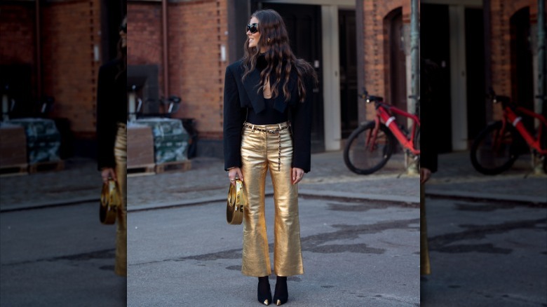 woman wearing black blouse and flared gold metallic pants