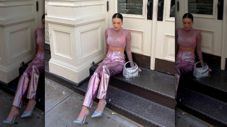 woman sitting on stairs wearing pink top with pink metallic pants