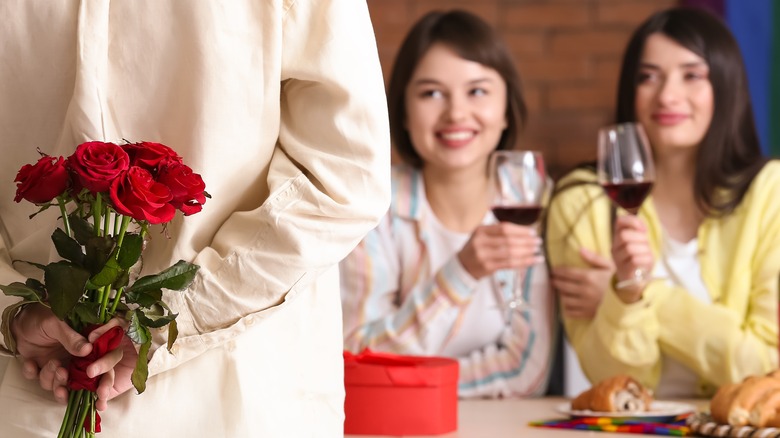 women with man holding roses