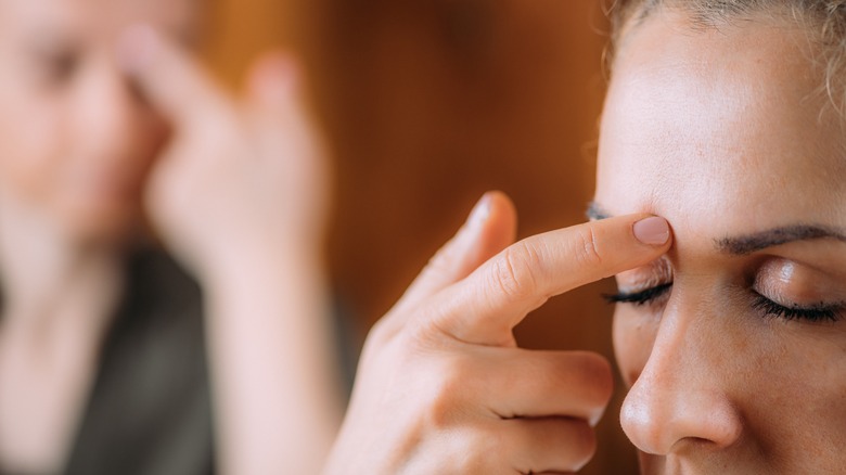 Woman taps acupressure point on forehead