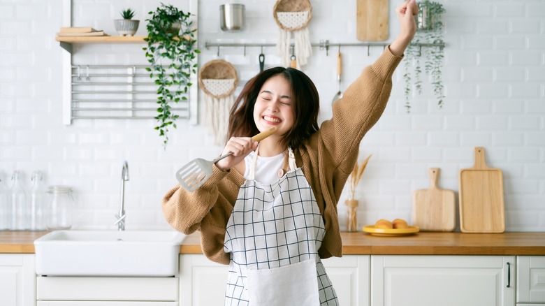 Woman dances and sings into spatula 