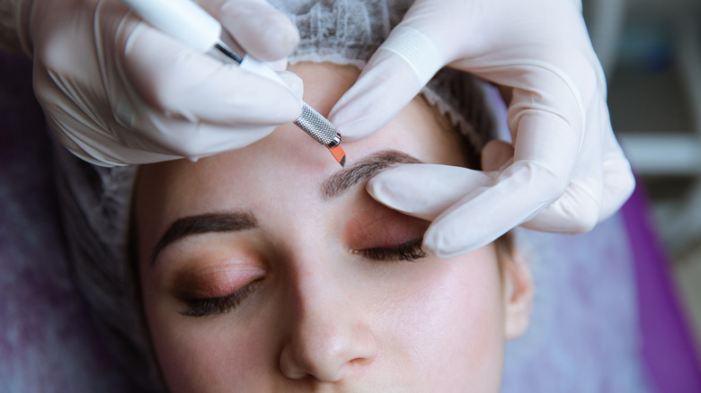 Woman getting eyebrow tattoo treatment