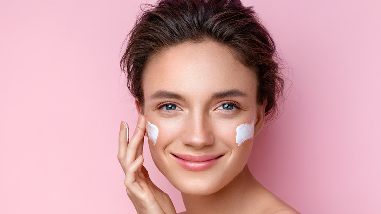 Woman applying moisturizer.