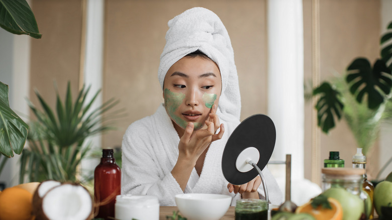 Woman applying green face mask