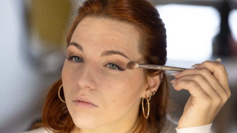 Woman applying eyeshadow while wearing false lashes