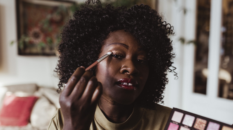 Woman with curly hair applying shimmery eyeshadow