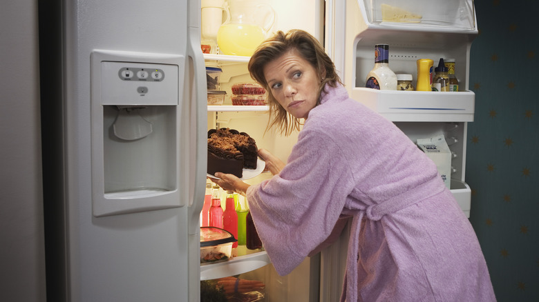 Woman sneaking cake out of fridge