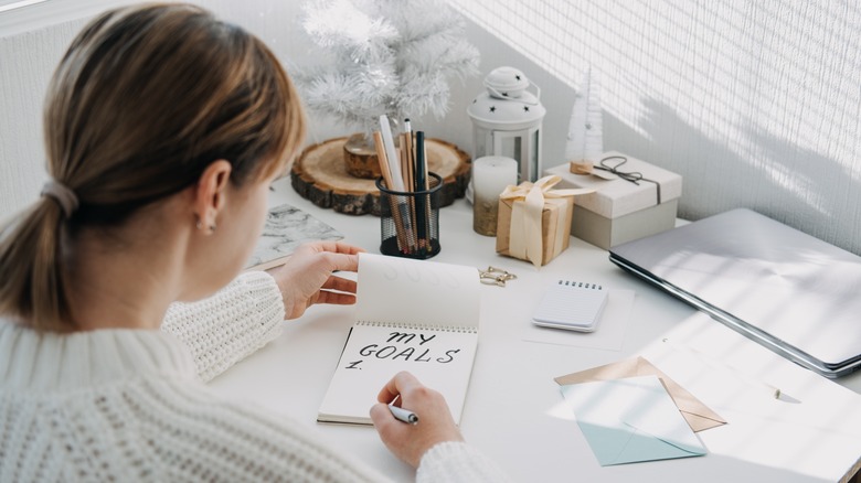 Woman writing goals at desk