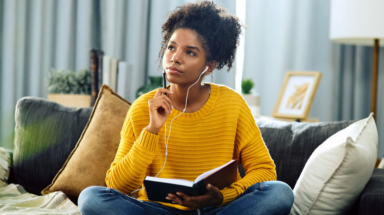 Woman in yellow sweater writing in a notebook