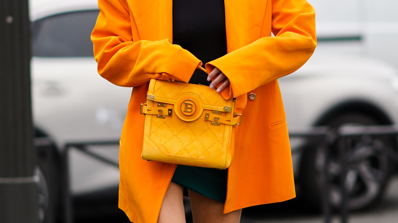 Woman with oversized orange blazer and logo purse