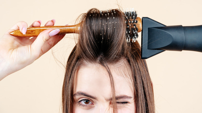 woman blowdrying hair with round brush