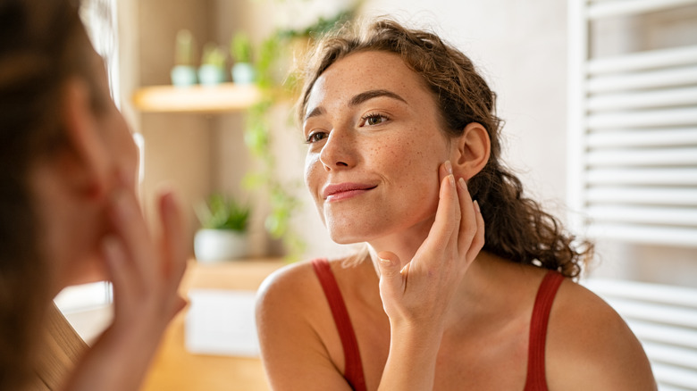 person looking at skin in mirror