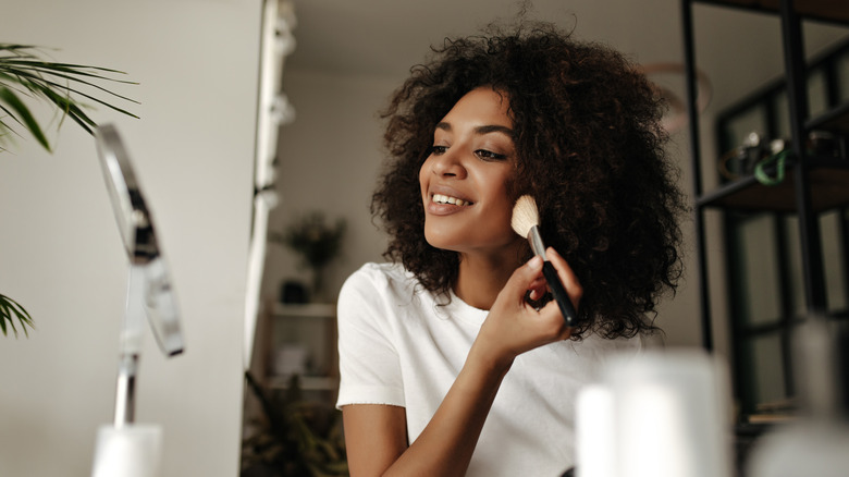 Young woman applying makeup with brush