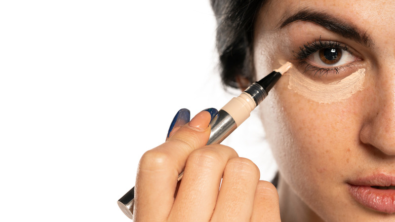 Woman applying concealer pencil