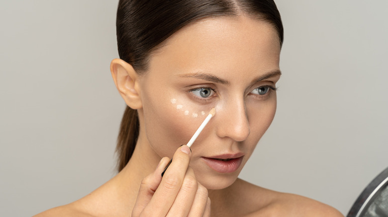 Woman applying concealer 