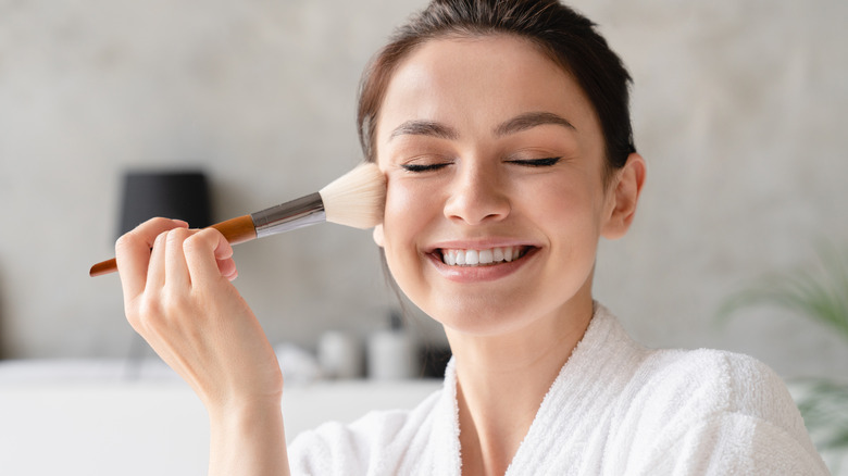 Woman applying powder on her face