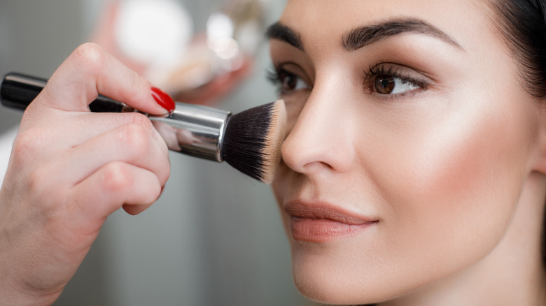 Woman applying concealer with a brush
