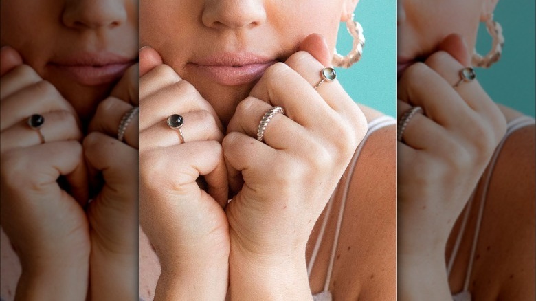 Woman with mood rings, posed with hands on chin